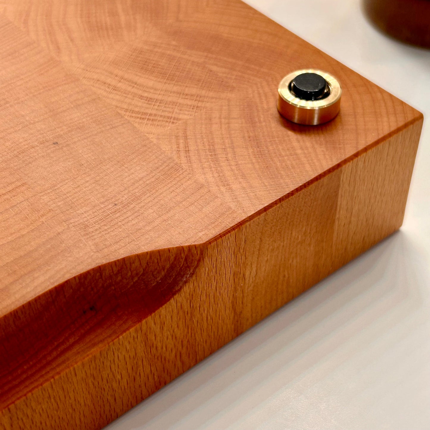 Gros plan sur les pieds en laiton massif d’une grande planche à découper artisanale en bois de bout en hêtre