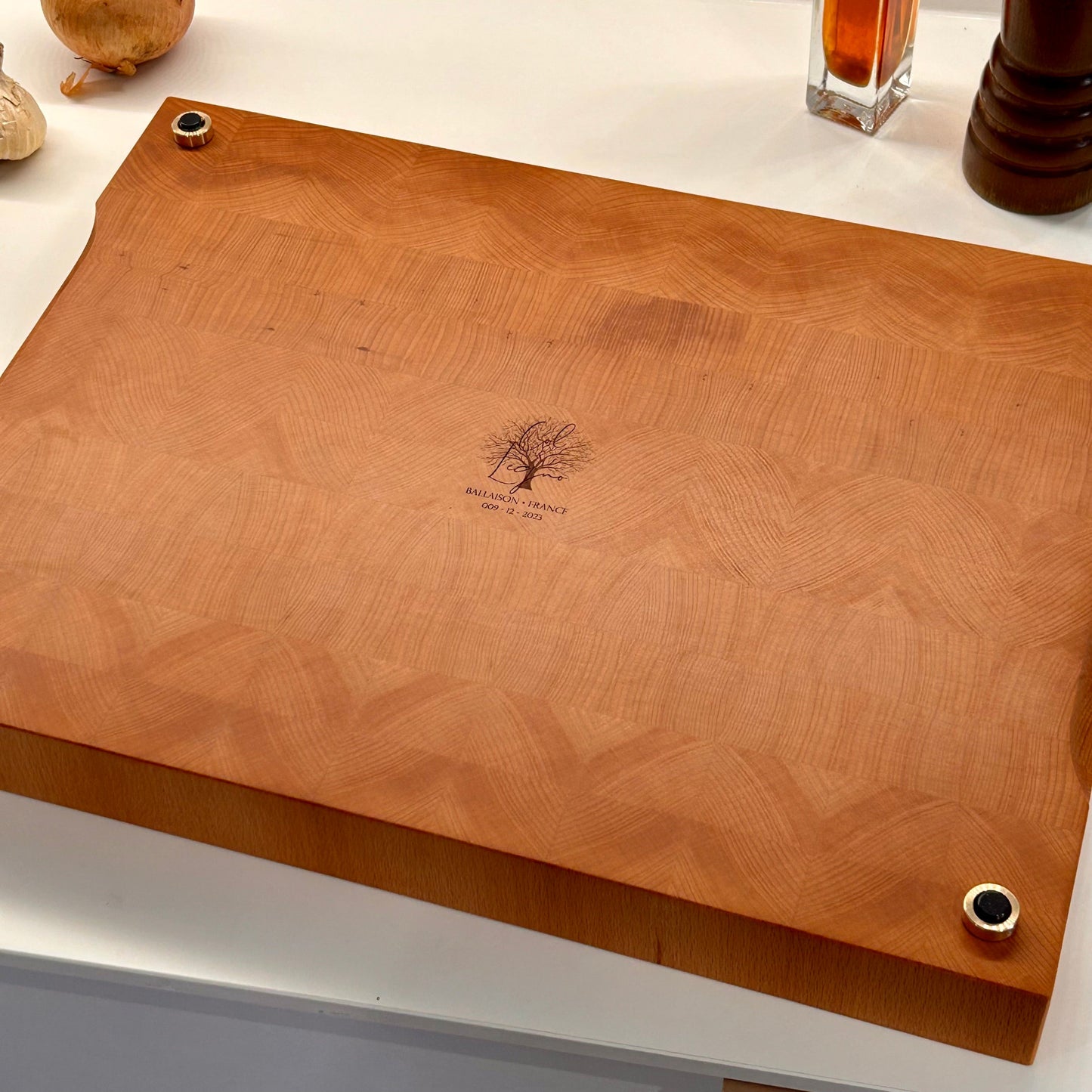 Vue de dessous d’une grande planche à découper en bois de bout en hêtre, avec logo gravé et pieds en laiton massif.