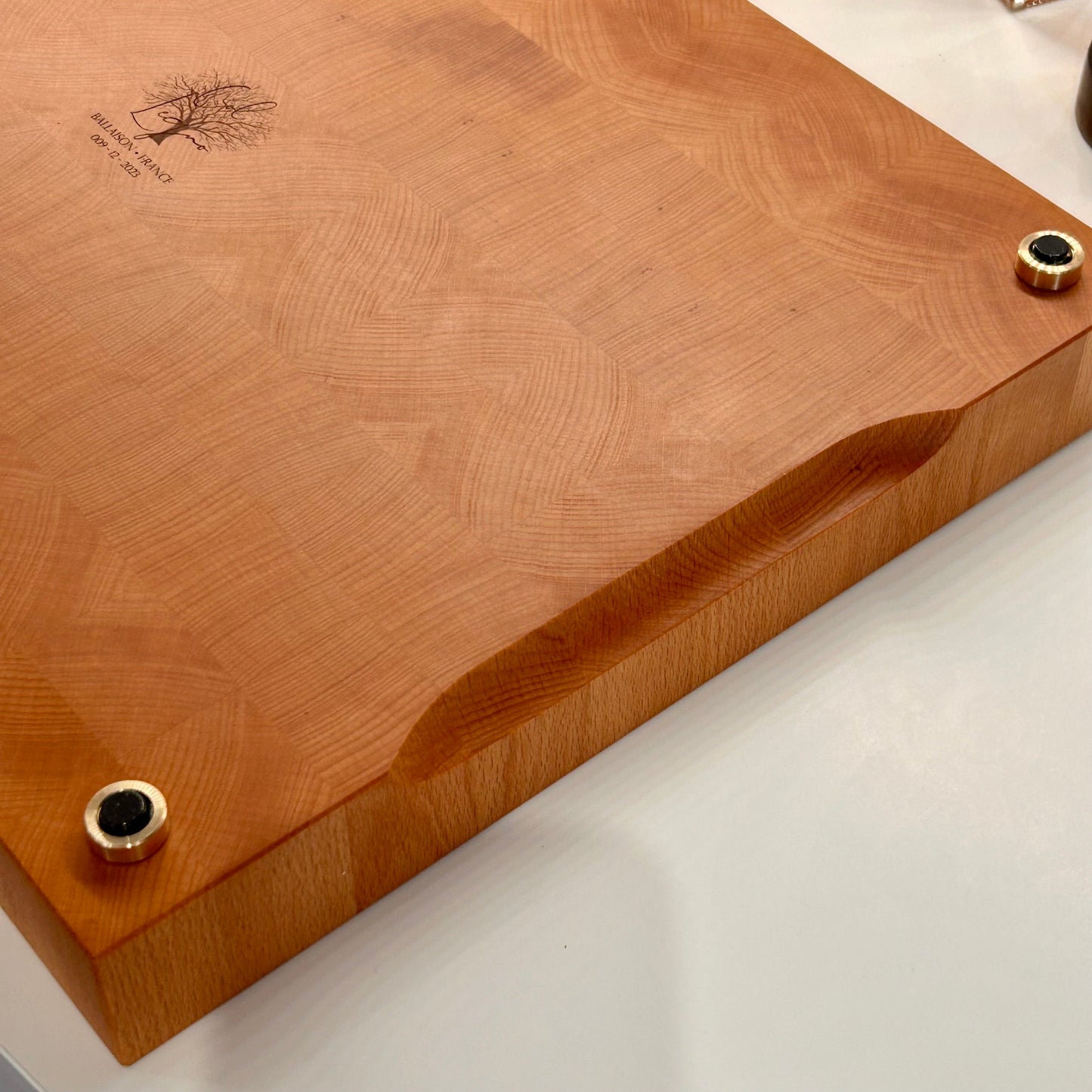 Détail de la poignée intégrée d’une grande planche à découper artisanale en bois de bout en hêtre,