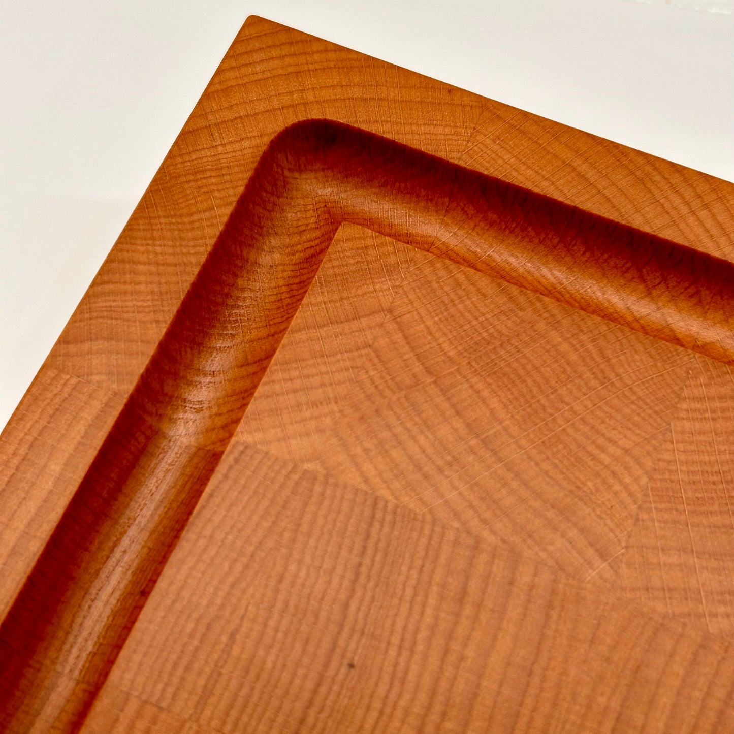 Détail de la rigole à jus et de la qualité de finition haut de gamme d’une grande planche à découper en bois de bout en hêtre.