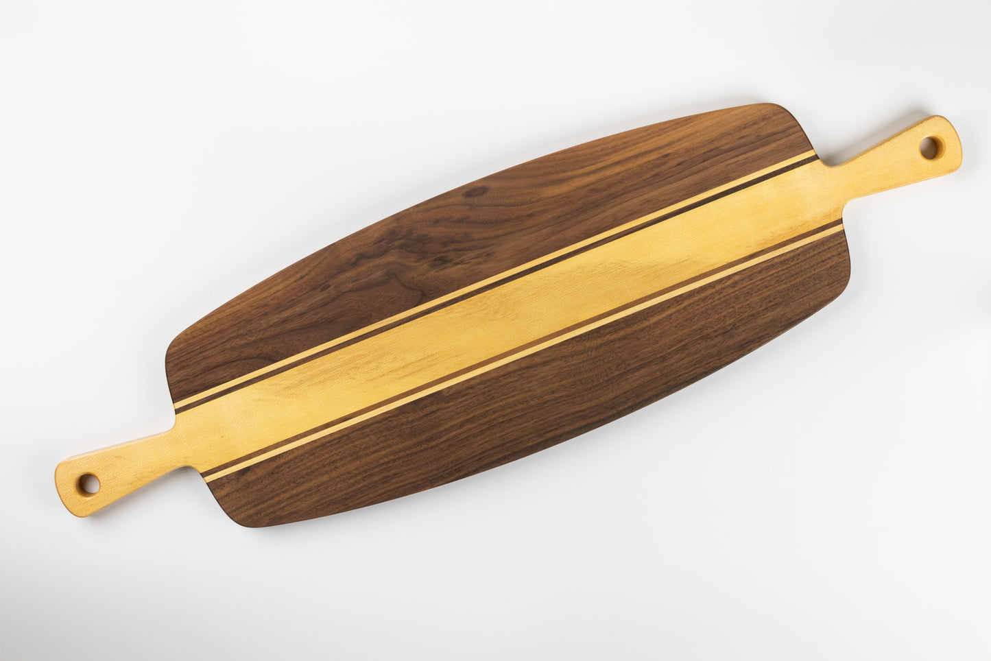 Planche apéro artisanale en noyer et érable, avec double poignée sculptée, fabrication française en bois massif et design graphique épuré.