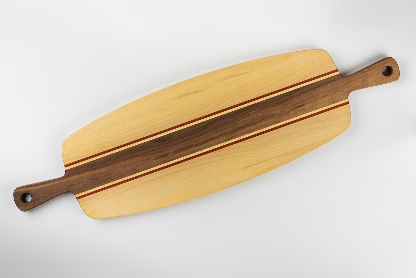 Planche apéro en bois massif fabriquée en France, avec poignées en noyer, plateau en érable et filets de padouk, design graphique à double poignée.