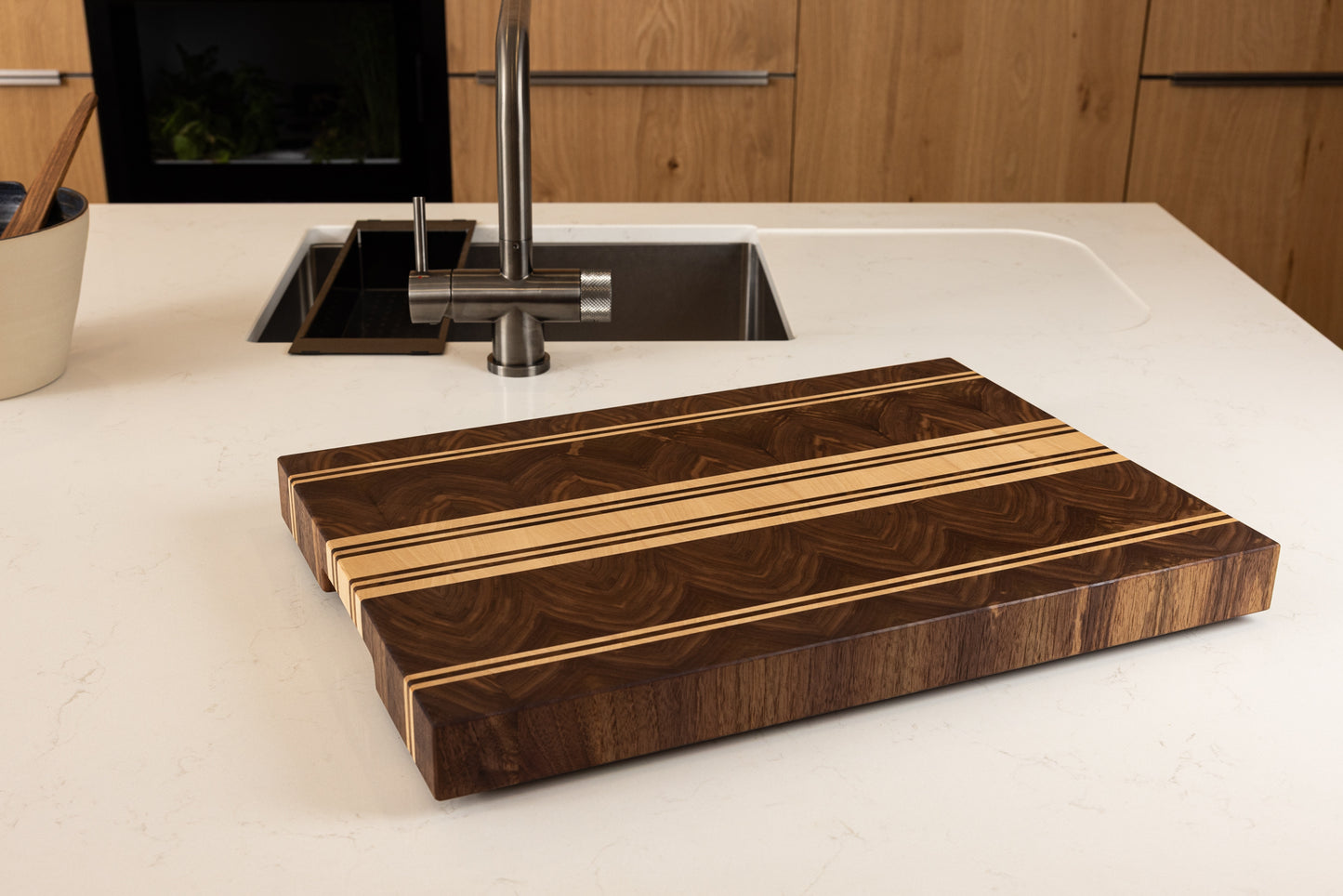 Planche à découper artisanale en bois de bout, posée sur un plan de travail en chêne dans une cuisine moderne, fabrication Made in France par un artisan d’art