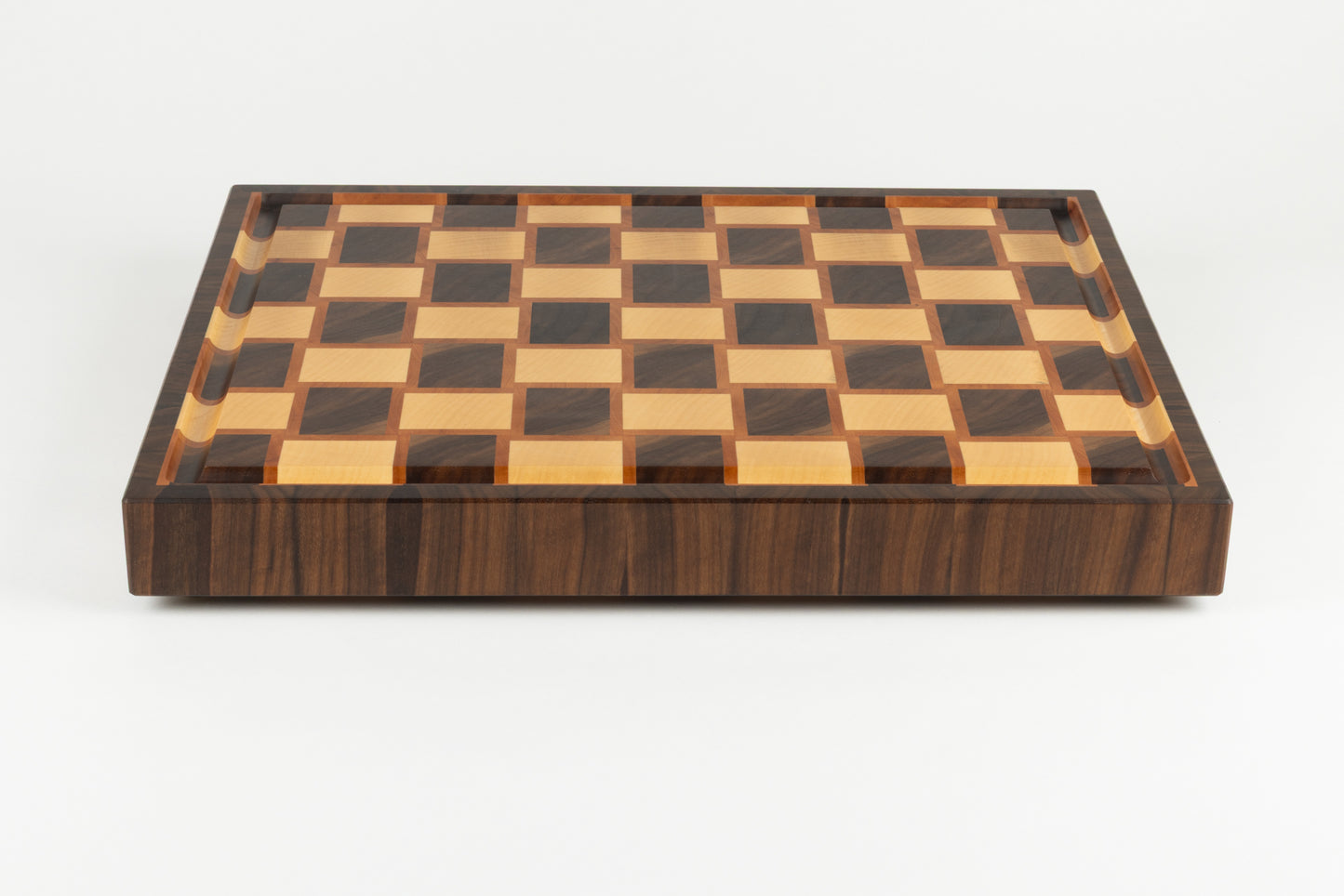 Vue de face d’une planche artisanale premium en bois de bout, bordure en noyer au veinage élégant et surface damier en érable, poirier et noyer américain.