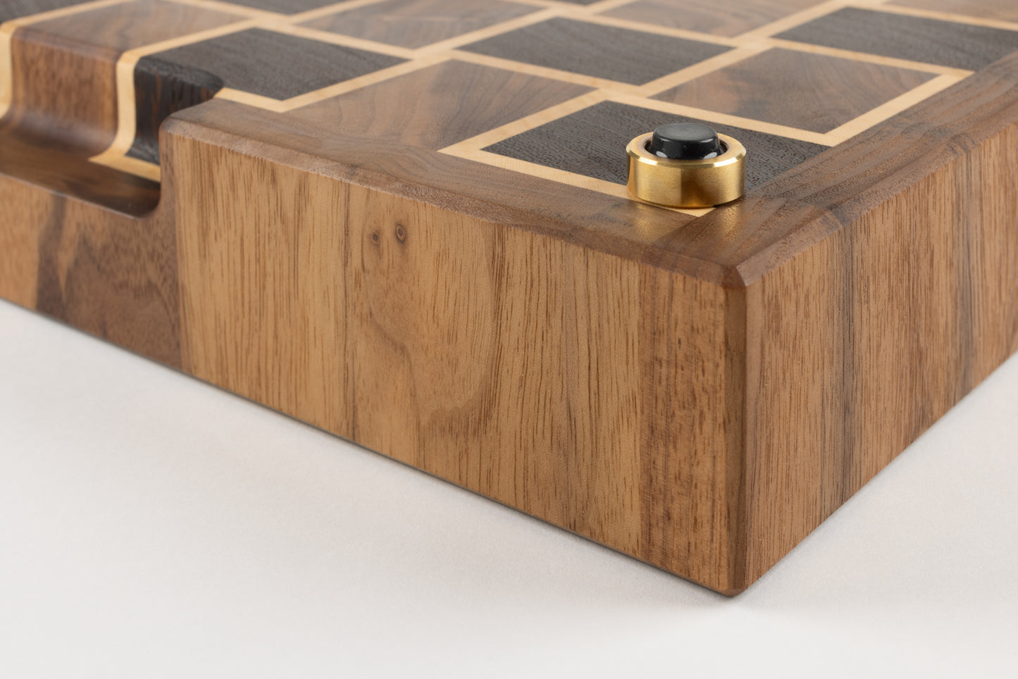 Vue rapprochée du coin d’une planche artisanale de luxe en bois de bout, dotée d’un pied en laiton massif français avec patin antidérapant et finitions biseautées soignées.