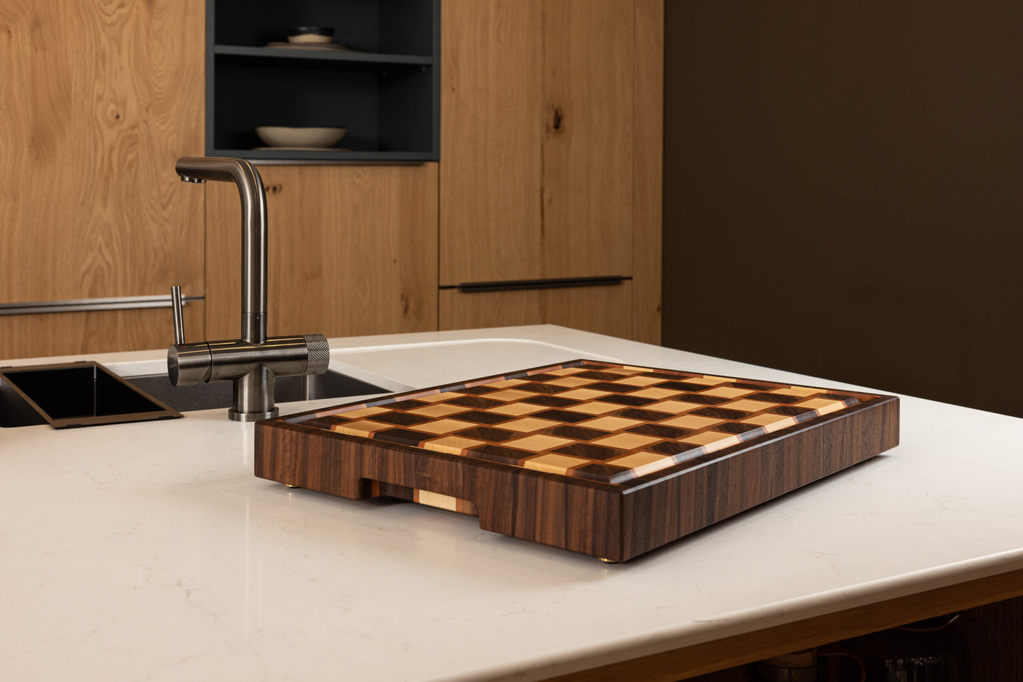 Vue sur une planche à découper en bois de bout luxueuse en noyer, érable et poirier sur un plan de travail de cuisine moderne haut de gamme.