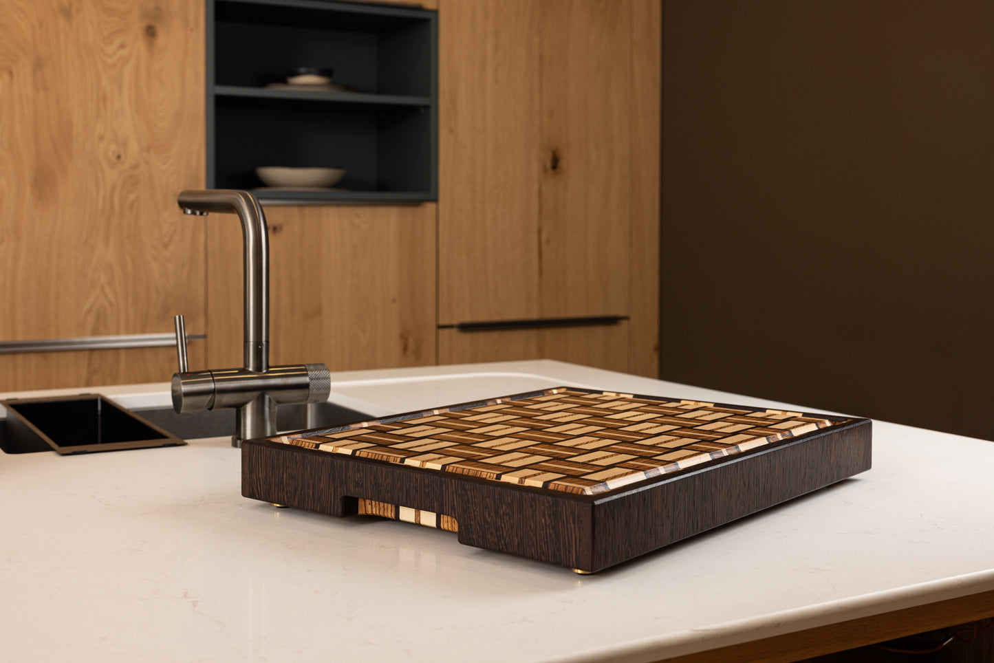 Planche à découper en bois de bout modèle Berlioz, en zebrano, noyer et érable, vue sous un autre angle dans une cuisine moderne. Pièce artisanale fabriquée en France en bois précieux, avec rigole et finition soignée