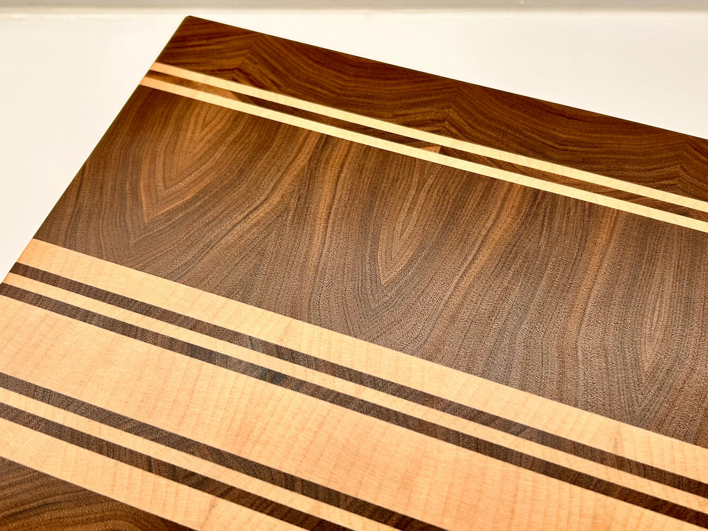 Vue de dessus d'une planche artisanale en noyer français et érable, surface finement poncée et lustrée à la cire
