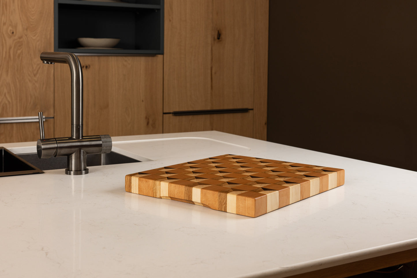 Planche à découper 3D Cube en bois de bout multi-essences, design graphique trompe-l’œil, en situation dans une cuisine moderne en chêne, artisanat français haut de gamme.