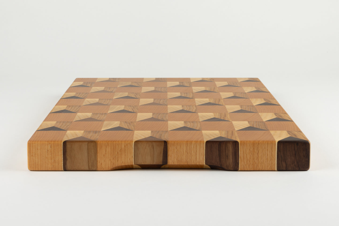 Vue latérale de la planche à découper Cube avec détail de la poignée fraisée, bois de bout chêne français, érable, hêtre et noyer américain, artisanat français haut de gamme.