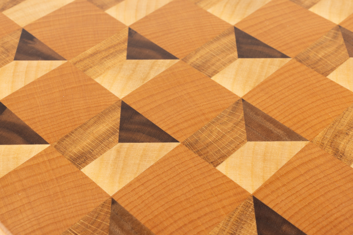 Gros plan sur le motif cubique trompe-l’œil 3D de la planche à découper Cube, réalisé en bois de bout chêne français, érable, hêtre et noyer américain, artisanat français haut de gamme.