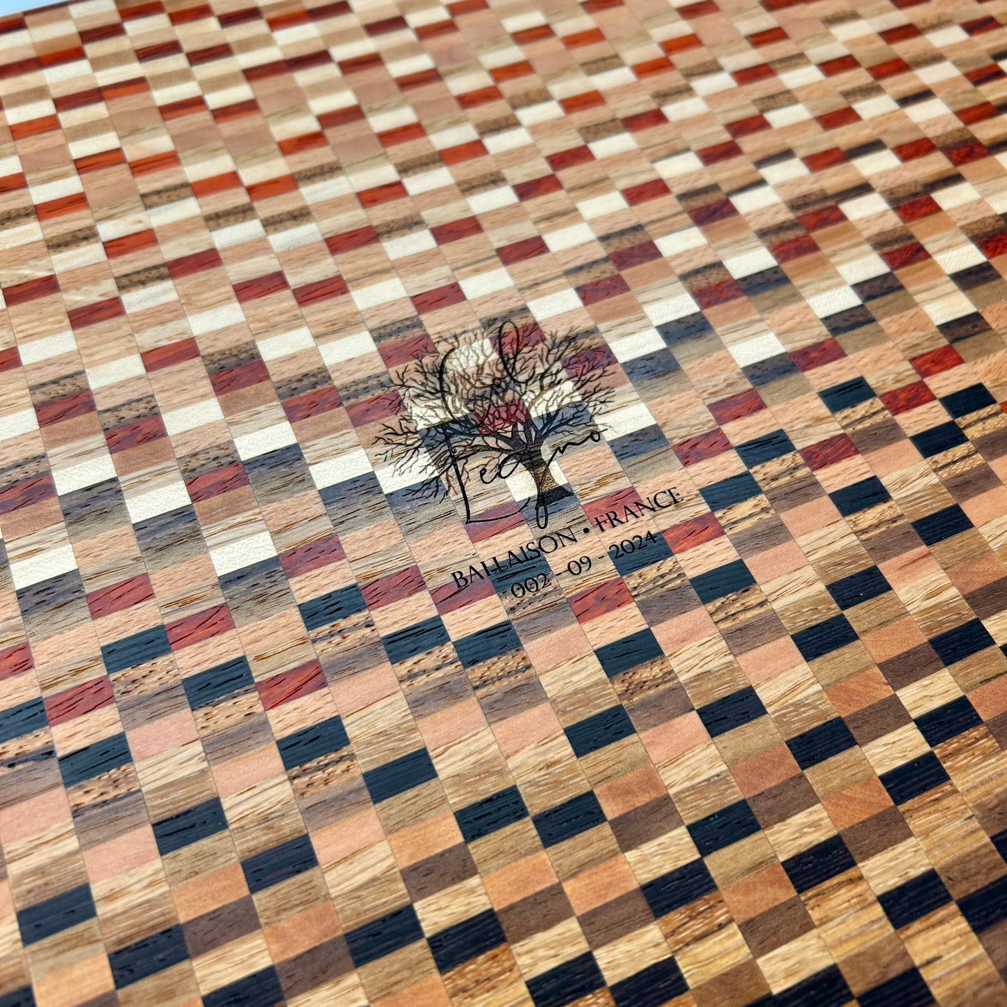 Détail du logo gravé au dos d’une planche à découper artisanale en bois massif. Finition soignée, design haut de gamme fabriqué en France.