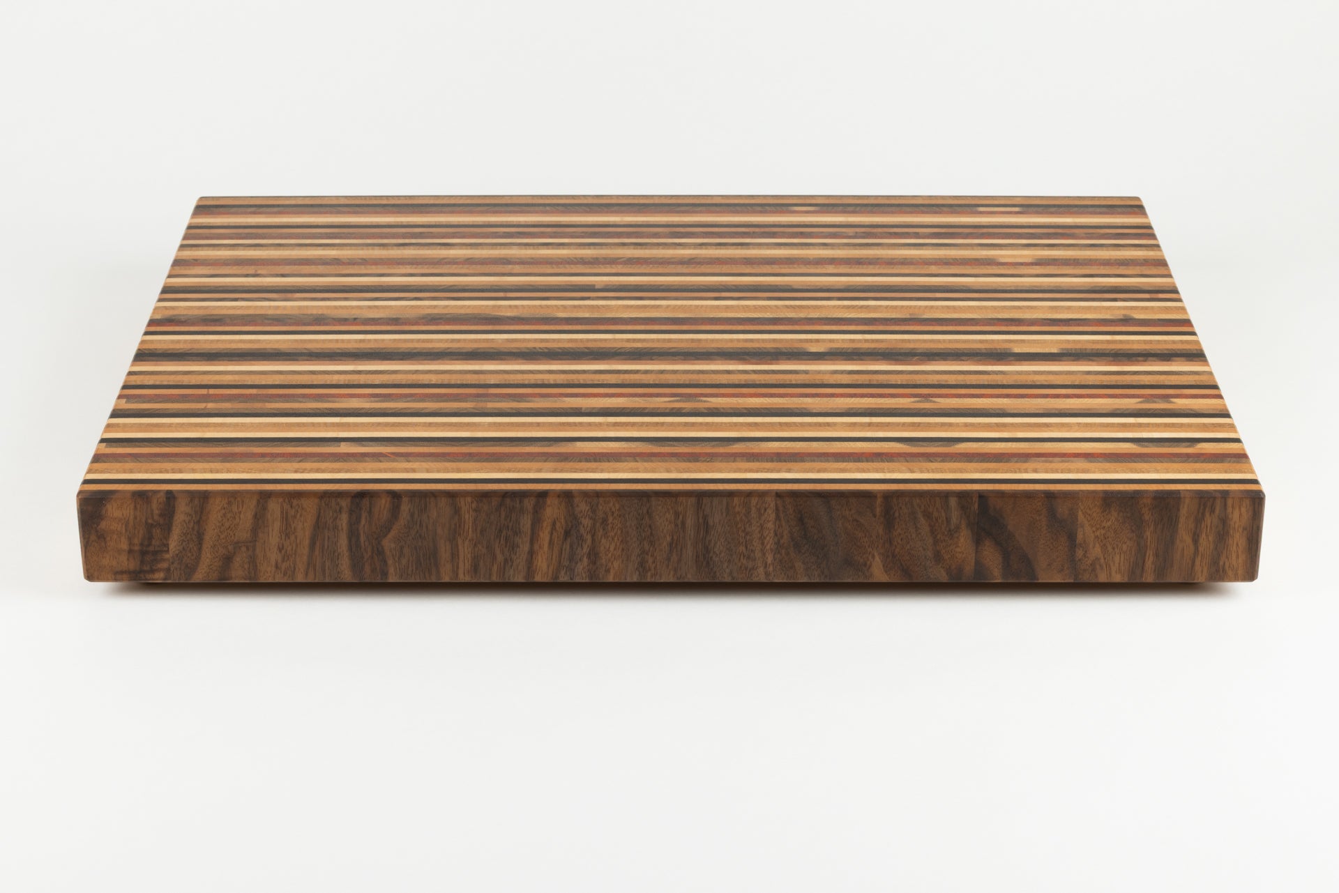 Vue de face de la planche Signature en bois de bout, laissant apparaître son design graphique moderne en 8 essences de bois nobles, fabrication Made in France par un artisan d’art.