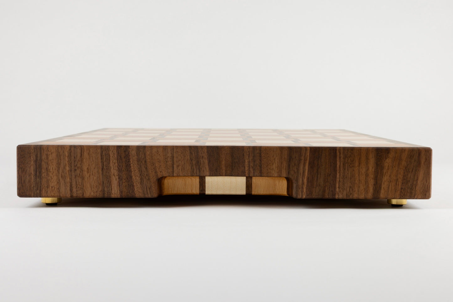 Planche à découper Berlioz en bois de bout multi-essences, vue latérale avec détail de la poignée fraisée élégante, motif damier tissé, artisanat français Made in France haut de gamme.