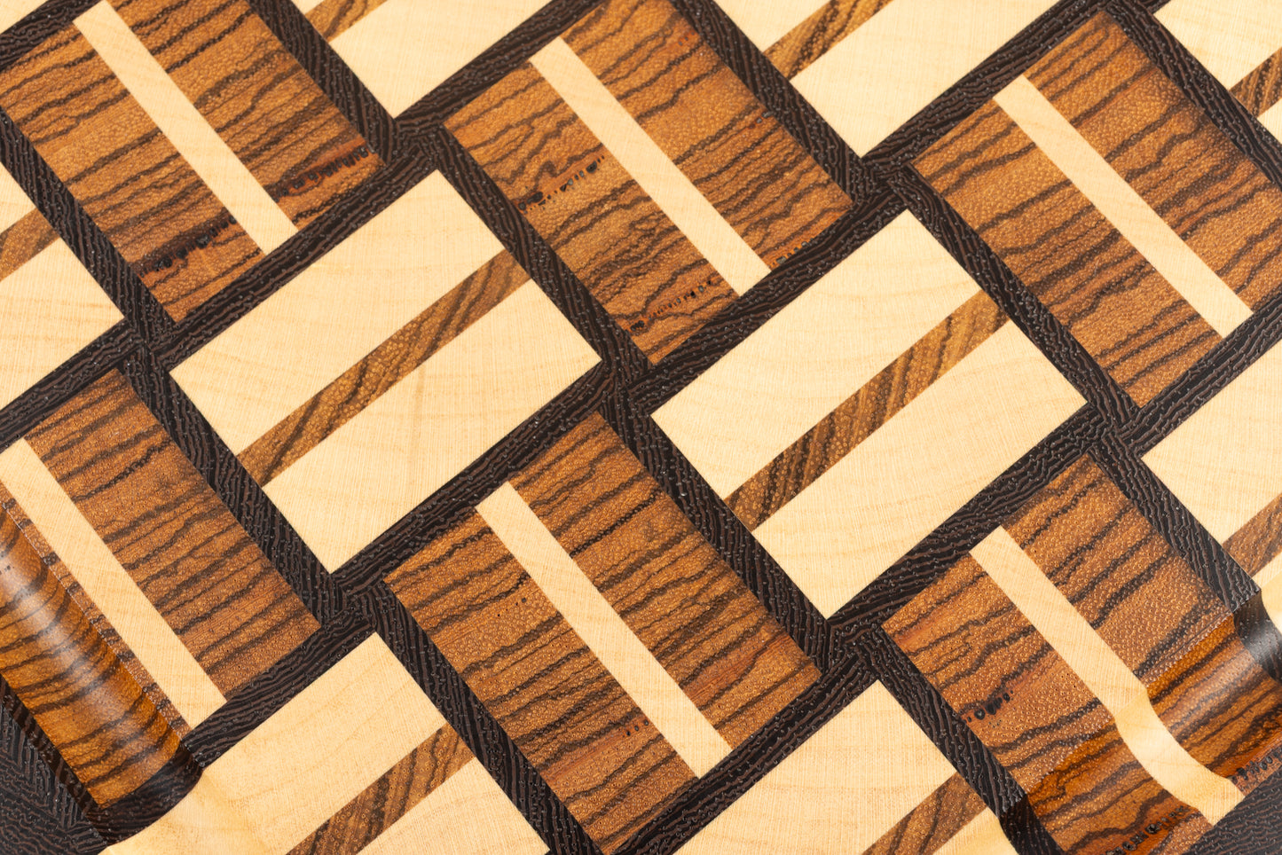 Planche à découper de luxe Berlioz, gros plan sur le motif en damier tissé, bois de bout en wengé, zebrano et érable, fabrication artisanale Made in France, finition raffinée et design élégant.
