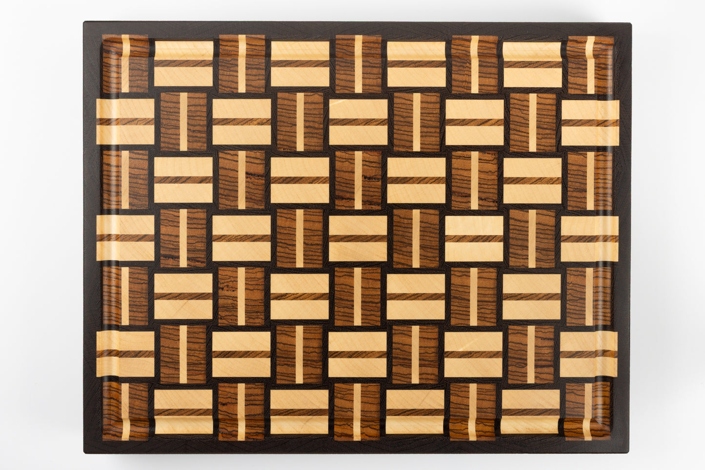 Planche à découper premium Berlioz en bois de bout, vue de dessus avec son design graphique damier tissé, essences précieuses wengé, zebrano et érable, finitions artisanales de prestige Made in France.