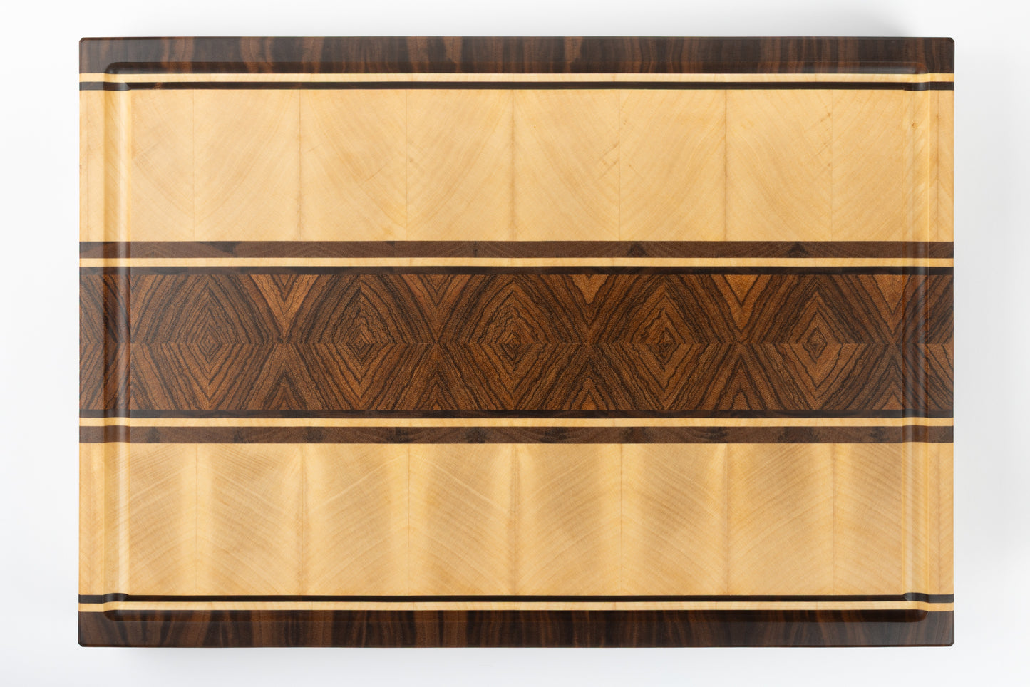 Vue de dessus de la planche à découper artisanale modèle Couperin, en bois massif de zebrano, érable et noyer américain, mettant en valeur le veinage naturel et l’élégance du design