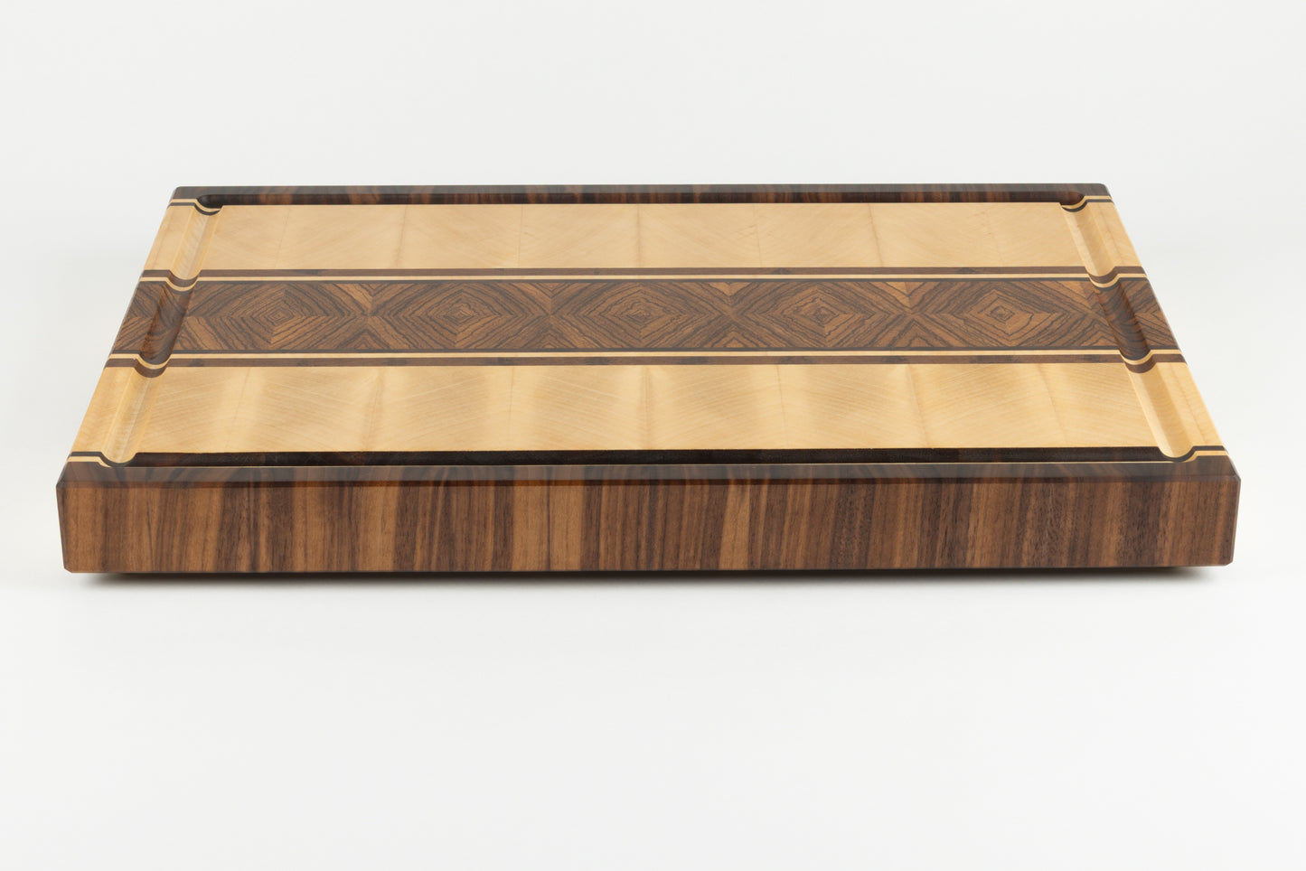 Vue globale de la planche à découper artisanale modèle Couperin en bois massif, présentant ses essences nobles de zebrano, érable et noyer américain.