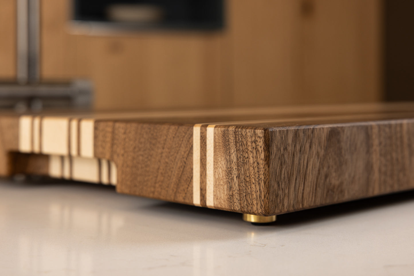 Planche à découper de luxe Debussy en noyer français et érable, détail rapproché du coin et veinage élégant, dans une cuisine moderne en chêne, fabrication Made in France haut de gamme