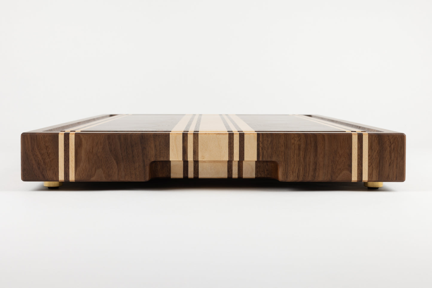 Planche à découper de luxe Debussy en noyer américain et érable, vue de côté avec pieds en laiton et finitions haut de gamme.