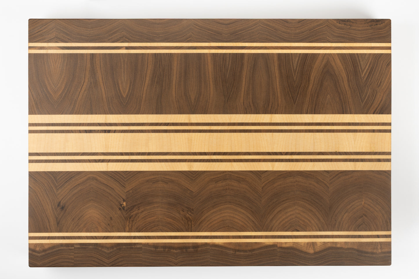 Planche à découper premium Debussy, vue de dessus en noyer français et érable, motif graphique sobre et raffiné, veinage au grain fin et finitions artisanales Made in France.