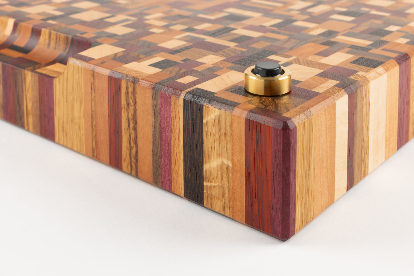 Vue rapprochée du coin de la planche à découper artisanale Messiaen, détail du pied en laiton massif Made in France avec patin antidérapant et arêtes finement biseautées.