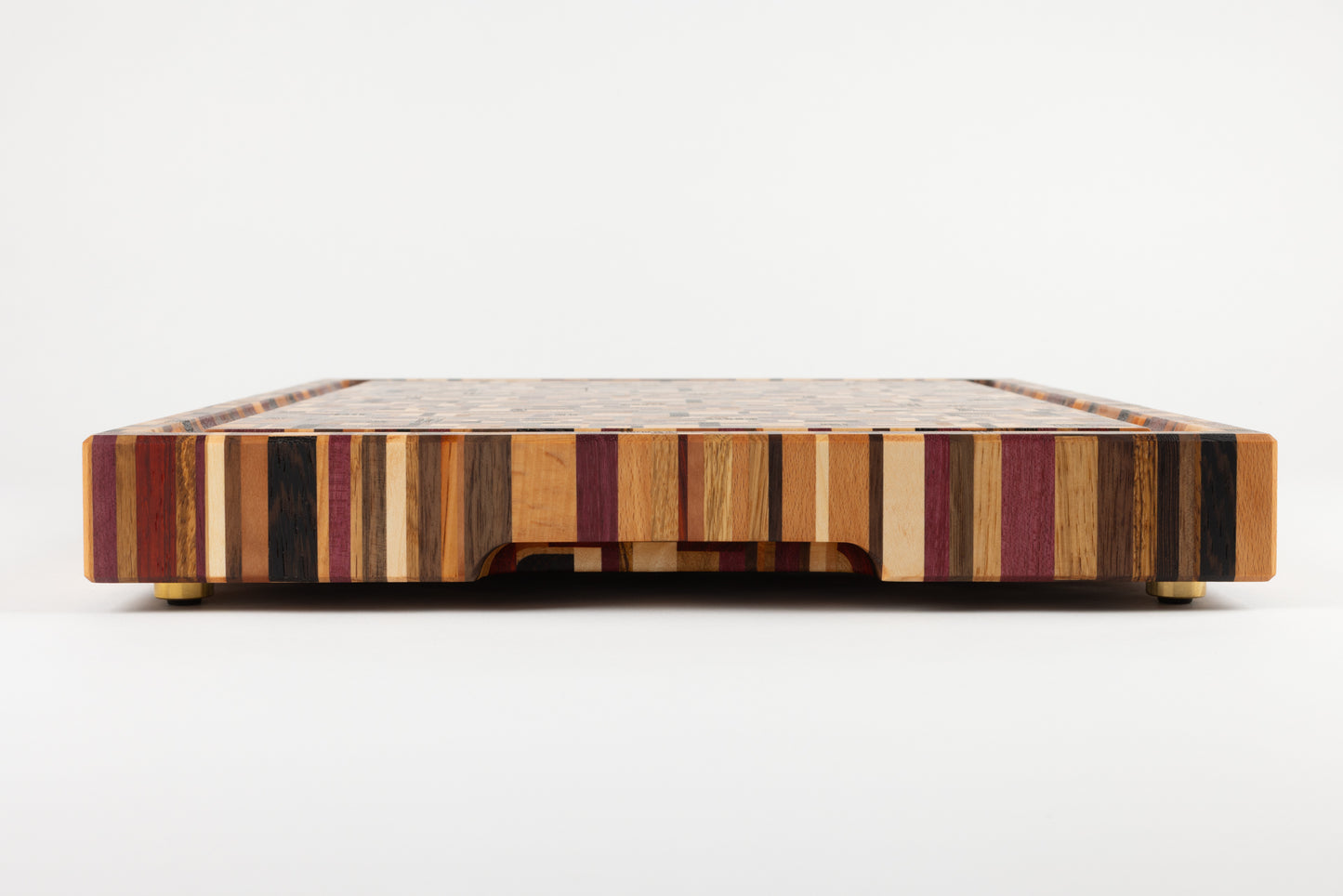 Planche à découper de luxe Messiaen, vue de côté mettant en valeur la poignée fraisée et les pieds en laiton haut de gamme.