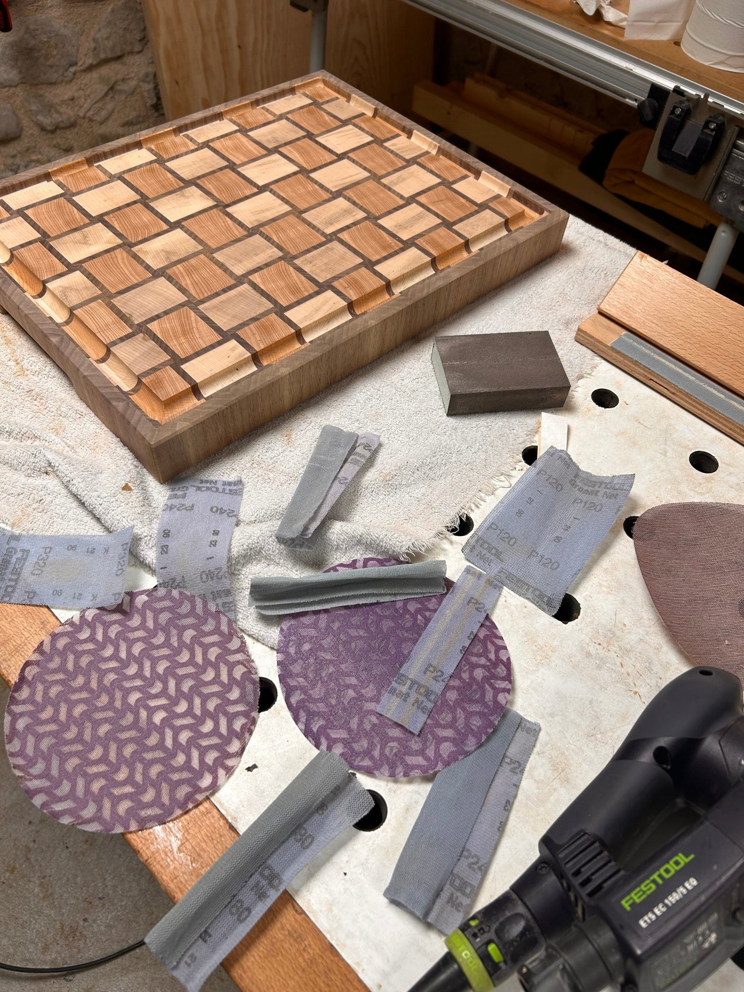 Opération de ponçage avec différents abrasifs sur une planche à découper artisanale en bois de bout