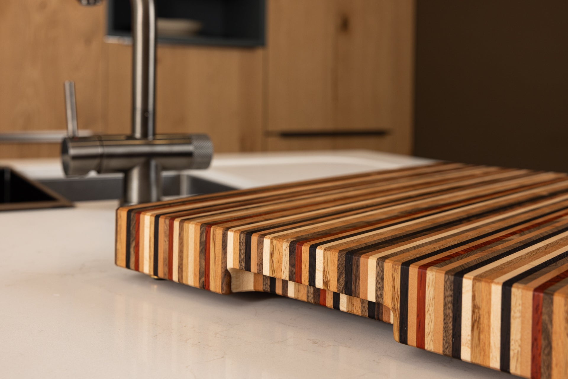 Vue rapprochée du côté d’une planche à découper artisanale premium Signature, mettant en valeur la poignée fraisée et son design raffiné, dans une cuisine contemporaine en chêne, fabrication française.