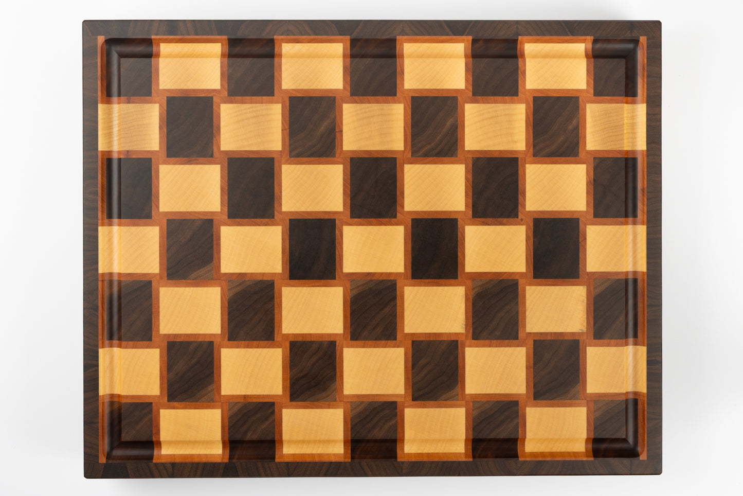 Vue de dessus complète d’une planche à découper artisanale en bois de bout, motif damier tressé en poirier, érable et noyer américain.