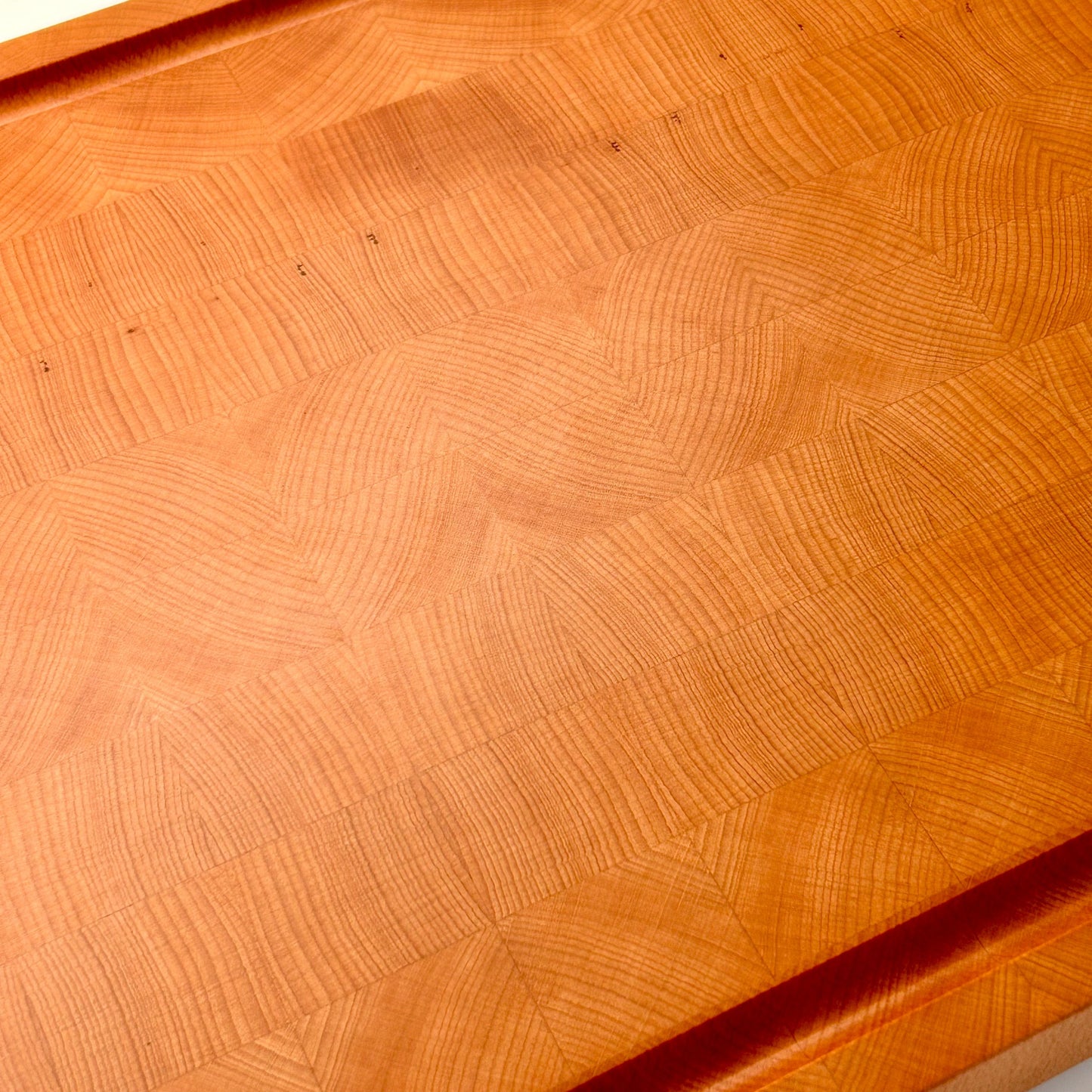 Vue de dessus d’une grande planche à découper en bois de bout en hêtre, avec veinage disposé de façon esthétique et soignée.