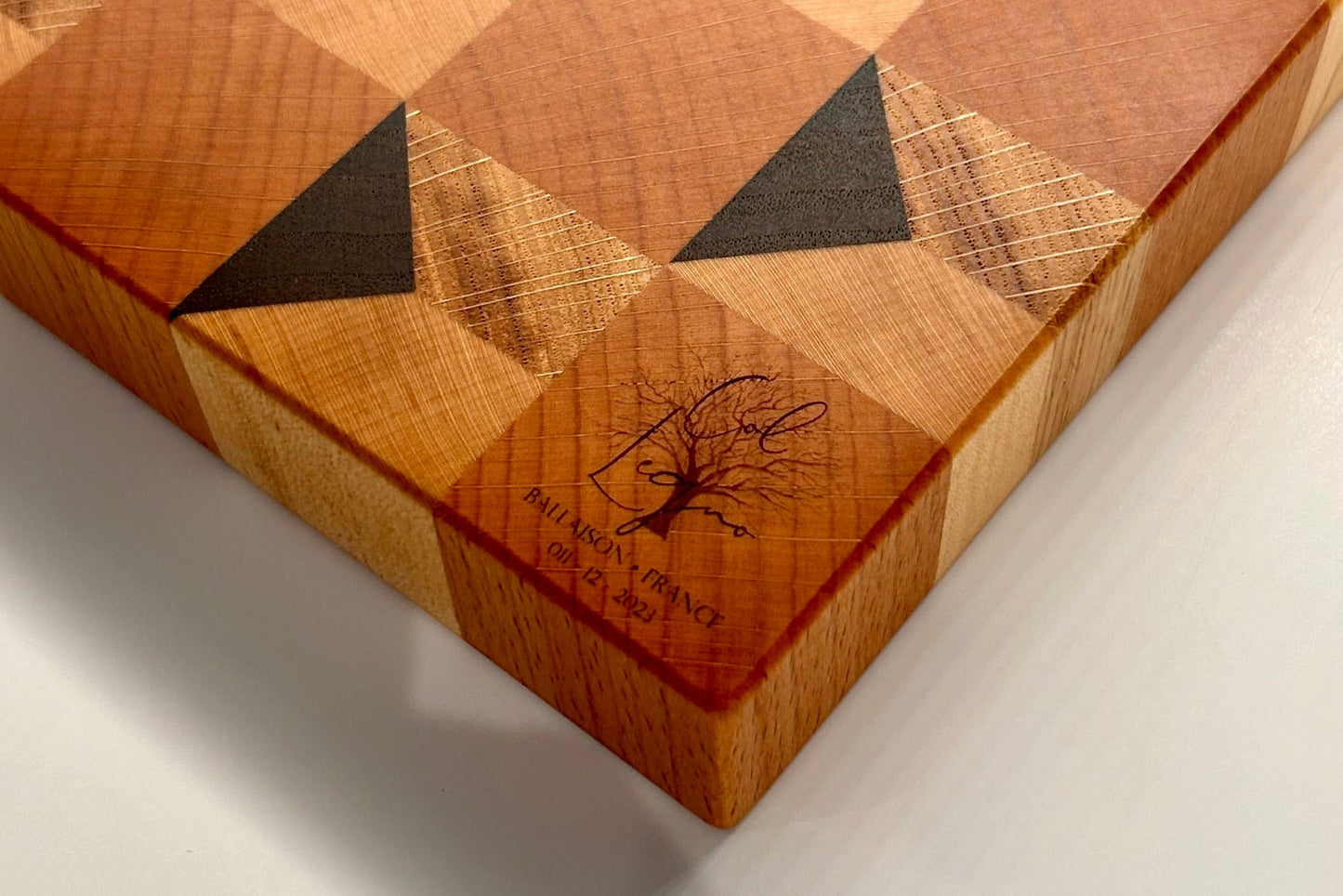 Détail du logo gravé sur une planche en bois massif artisanal, made in France.