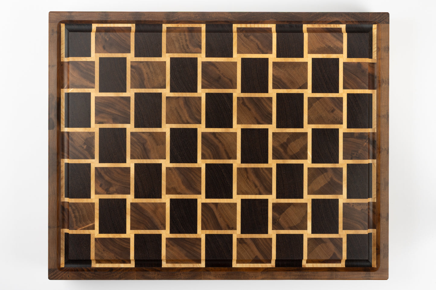 Planche à découper de luxe en bois massif, vue de dessus sur le motif damier tissé en noyer et érable, création artisanale Made in France.