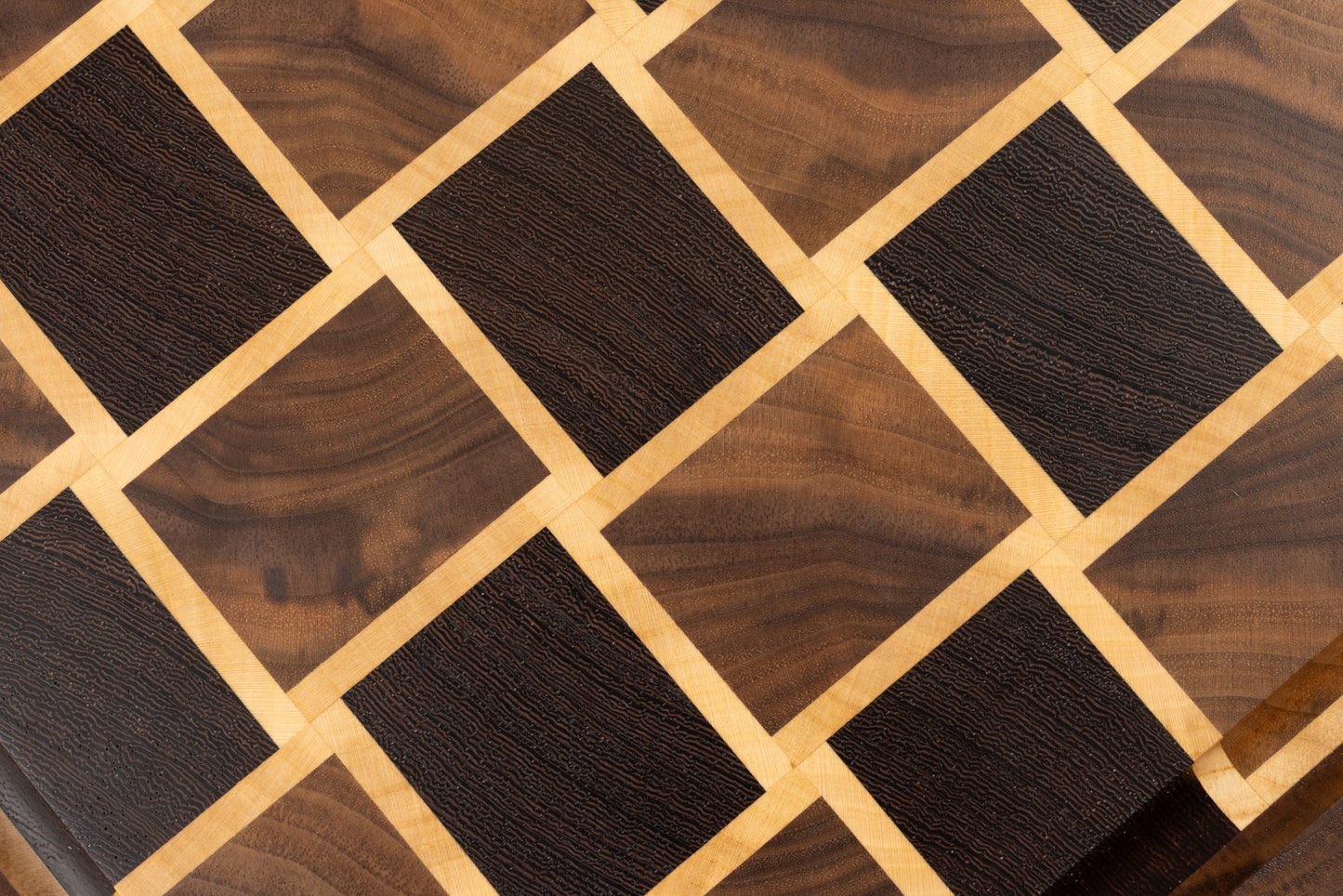 Gros plan sur le motif en damier d’une planche à découper artisanale en bois de bout, révélant le veinage naturel des essences de bois nobles.