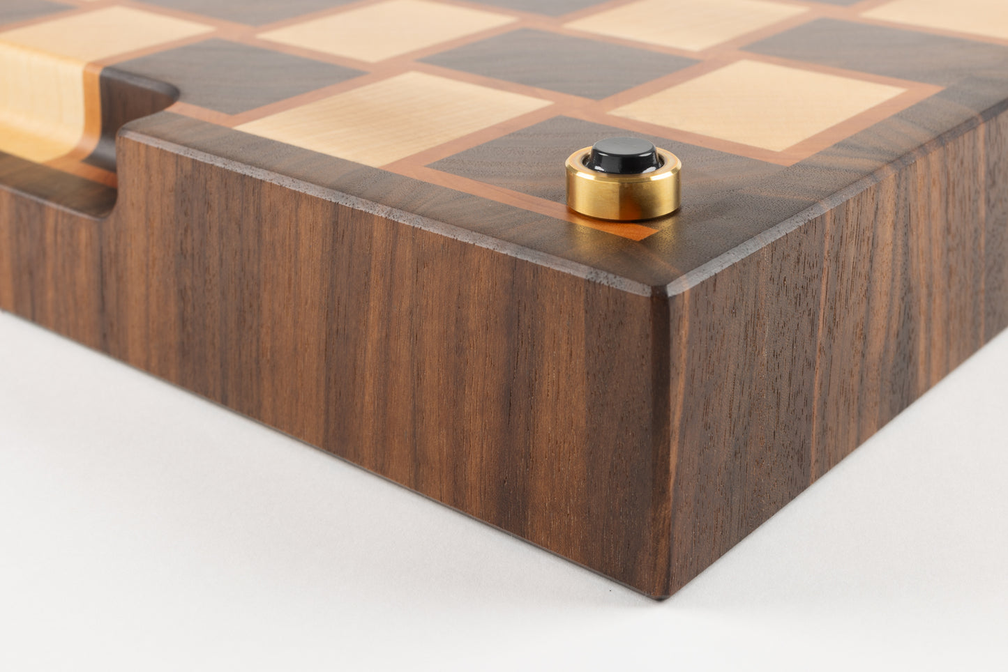 Détail haut de gamme d’une planche à découper en bois de bout, coin équipé d’un pied en laiton massif fabriqué en France avec patin antidérapant premium.