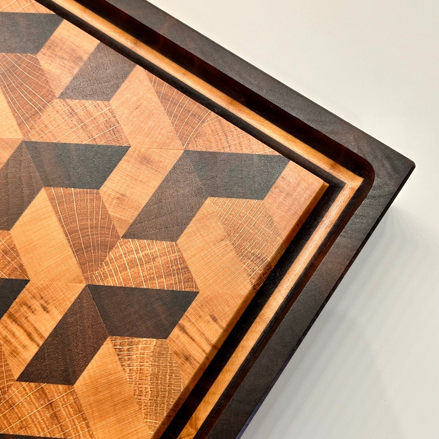 Vue de dessus du coin de la planche à découper effet trompe-l’œil 3D en bois de bout, montrant la rigole à jus en détail.