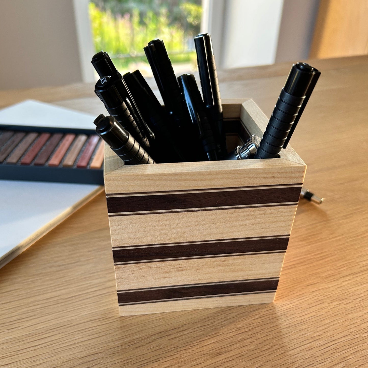 Vue rapprochée du pot à crayons Debussy en érable avec des bandes fines en noyer américain