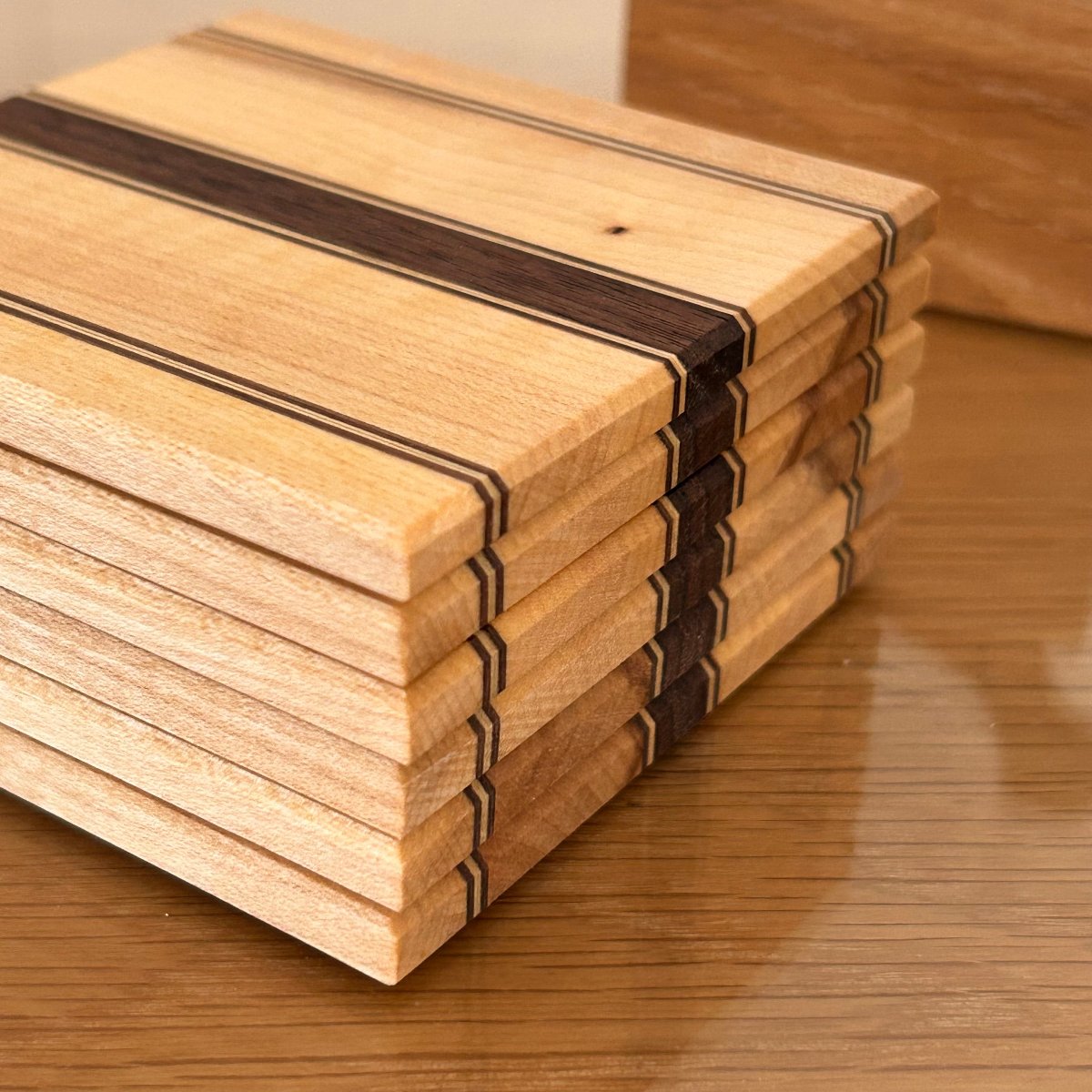Détail des rayures fines sur des sous-verres en bois artisanal, érable et noyer avec une finition huilée naturelle.