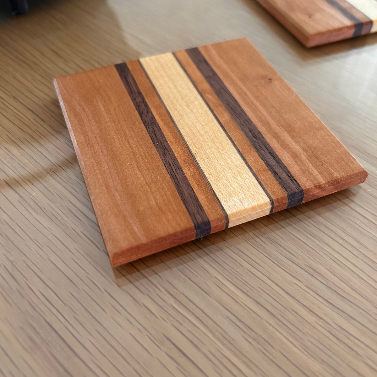 Sous-verres en bois artisanal fabriqué en France, avec un design géométrique à rayures fines, intemporel et élégant.