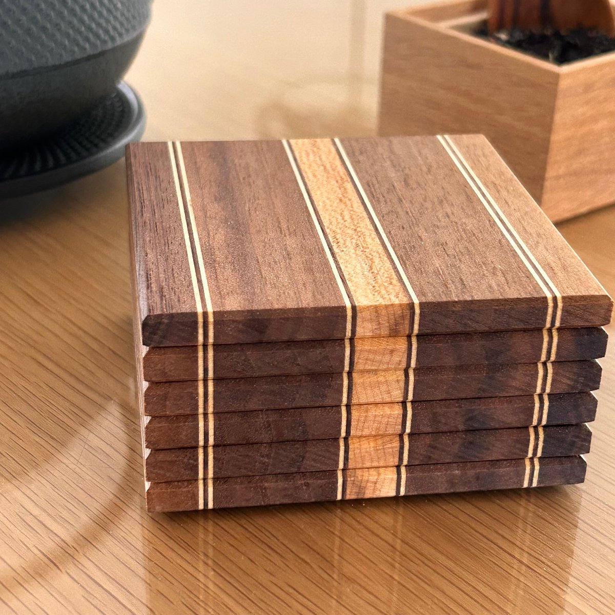 Sous-verres en bois Made in France combinant noyer et érable, avec des rayures fines et un contraste élégant.