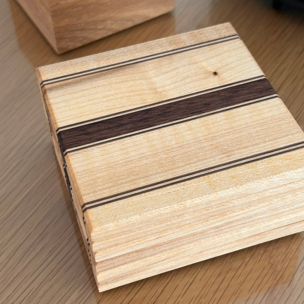 Sous-verres en bois artisanal Made in France, érable et noyer, avec des bandes fines et un veinage naturel.