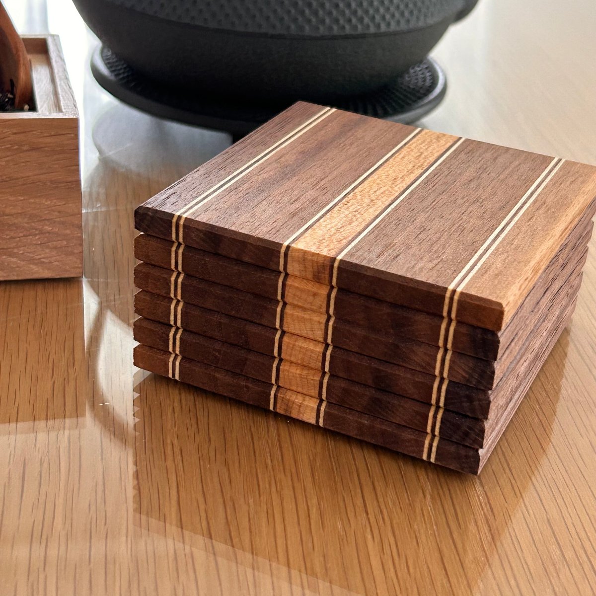 Sous-verres en bois de noyer, design artisanal avec rayures fines et élégantes.