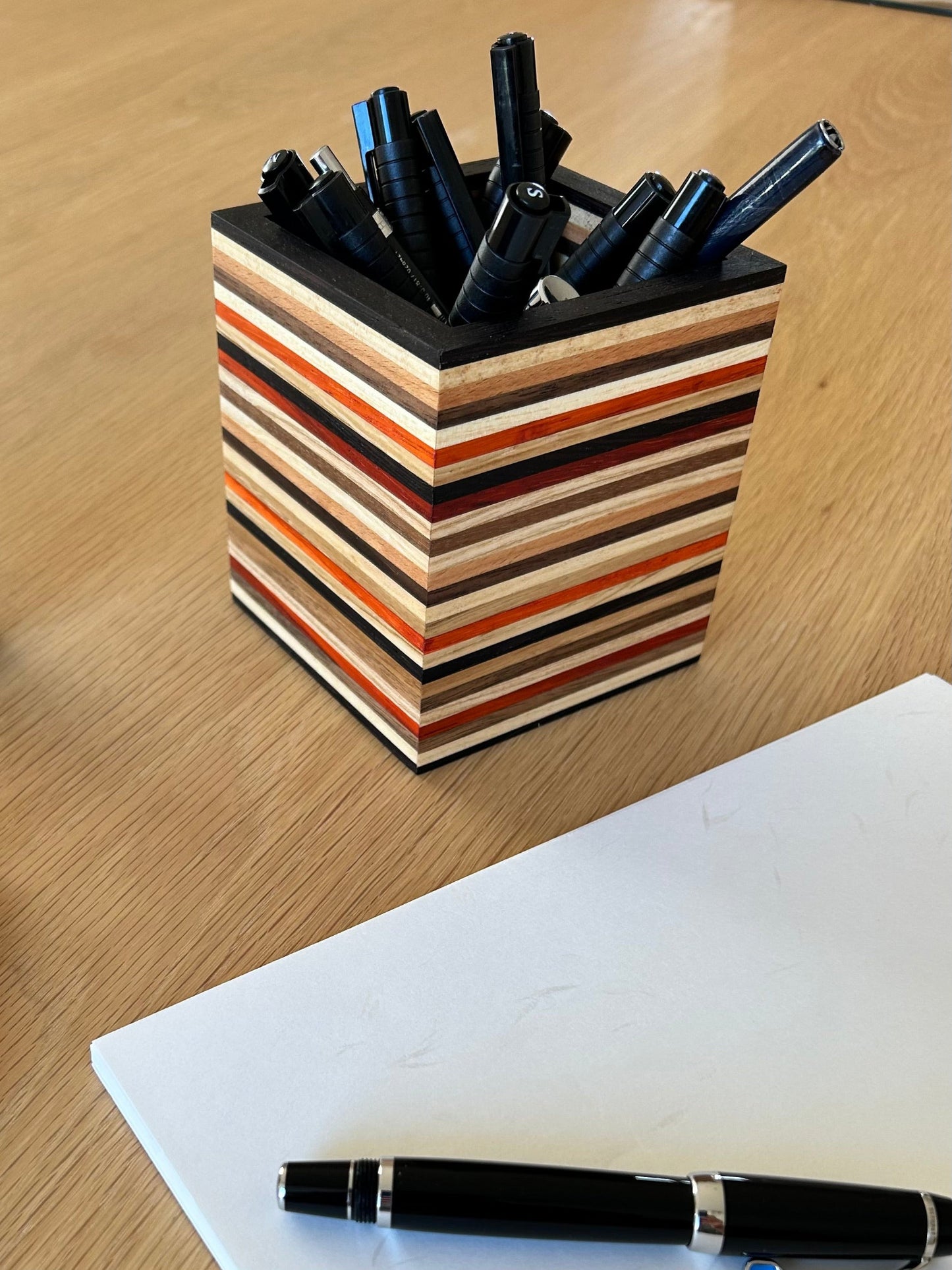 Pot à crayons en bois massif composé de 8 essences, avec un design multi-lignes élégant et original.