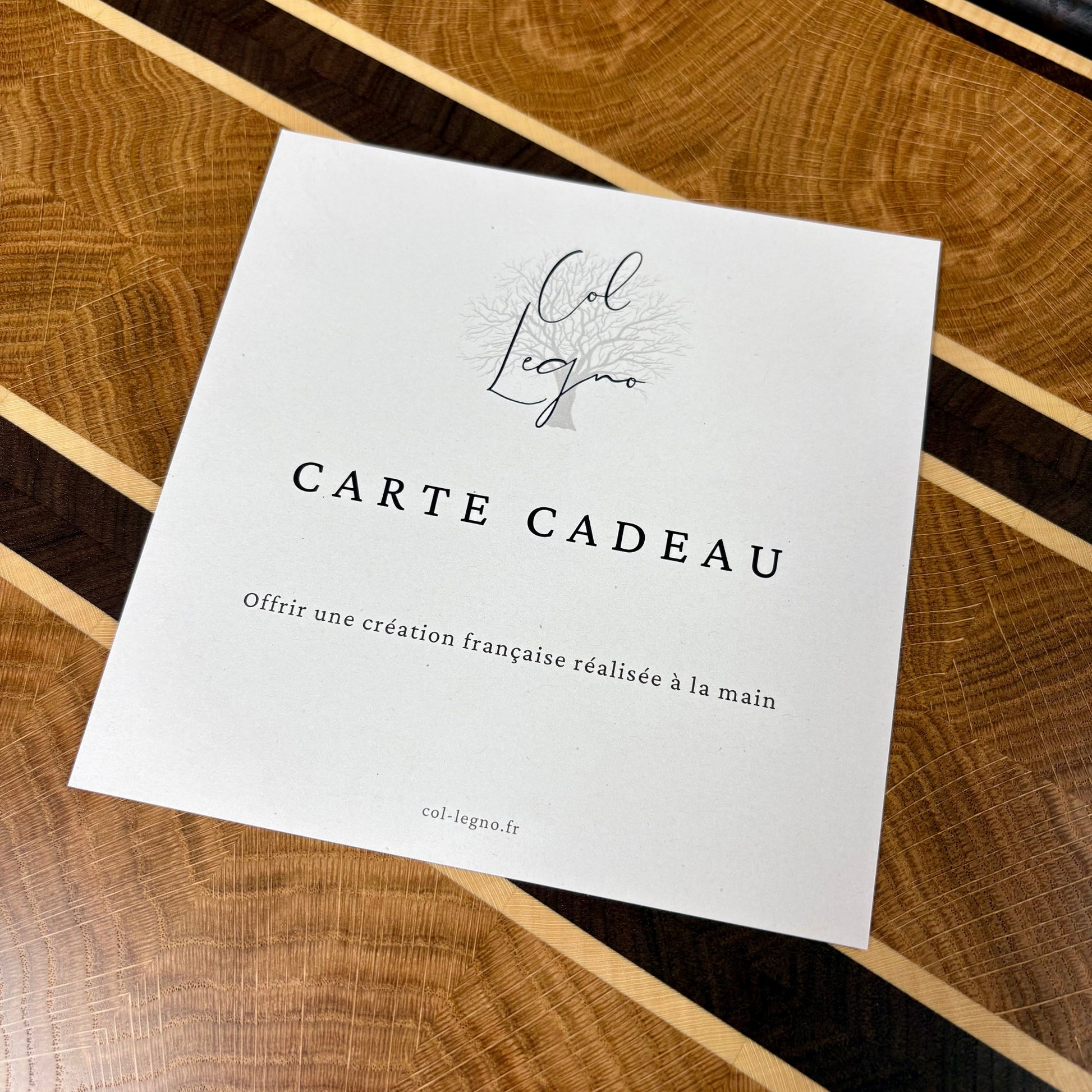 Carte cadeau artisanale Col Legno présentée sur une planche à découper haut de gamme en bois massif.