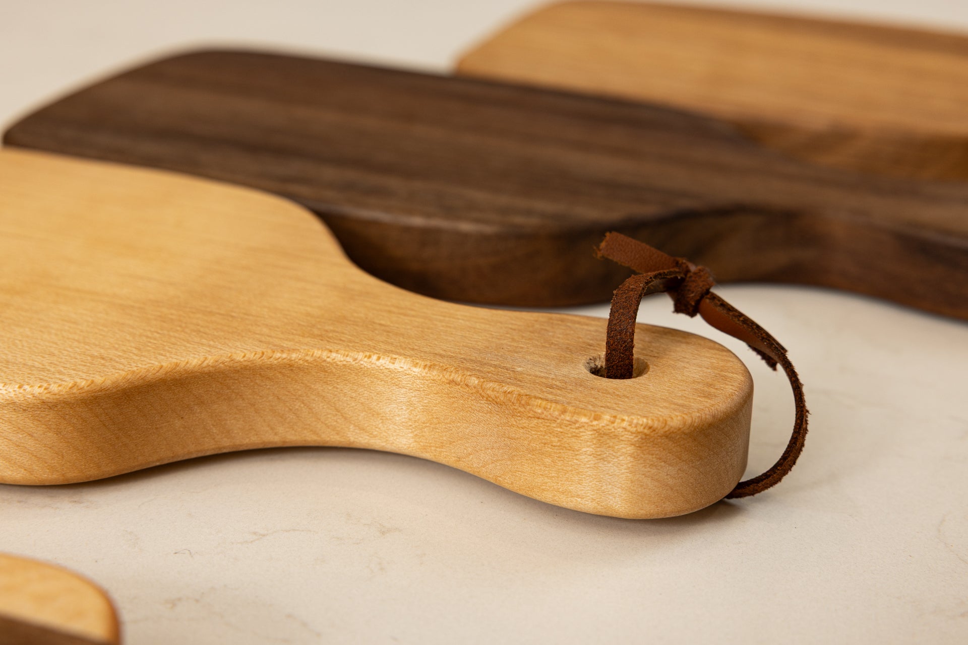 Vue de la mini planche à découper artisanale Piccolo en érable massif, veinage clair et d'une grande finesse, avec lanière en cuir et finitions haut de gamme Made in France.