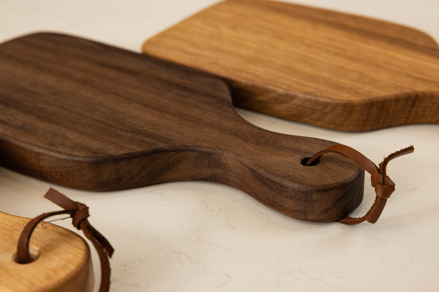 Vue de la mini planche à découper artisanale Piccolo en noyer américain massif, avec lanière en cuir élégante et finitions haut de gamme Made in France.
