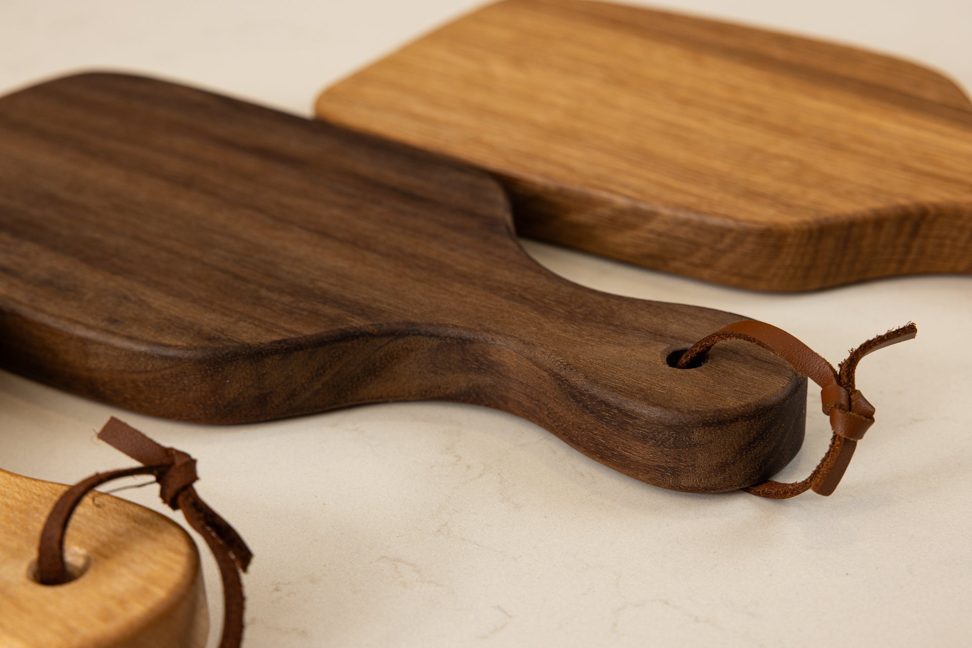 Vue de la mini planche à découper artisanale Piccolo en noyer américain massif, avec lanière en cuir élégante et finitions haut de gamme Made in France.