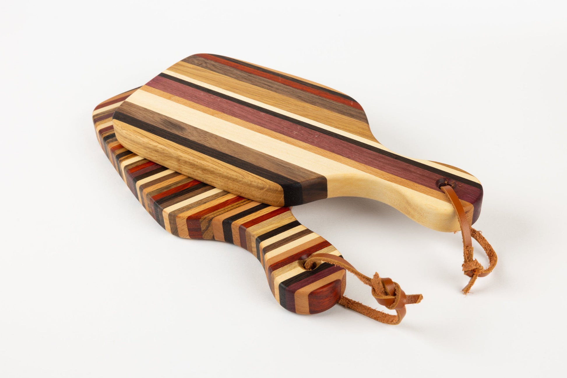 Détail des lanières en cuir sur deux mini planches artisanales en bois massif fabriquées en France.