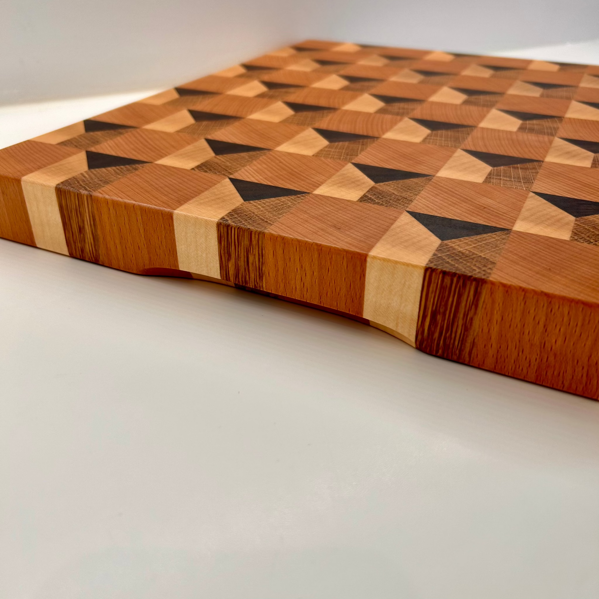 Planche à découper artisanal en bois massif vue sur la tranche avec poignée, effet 3D, luxe made in France.