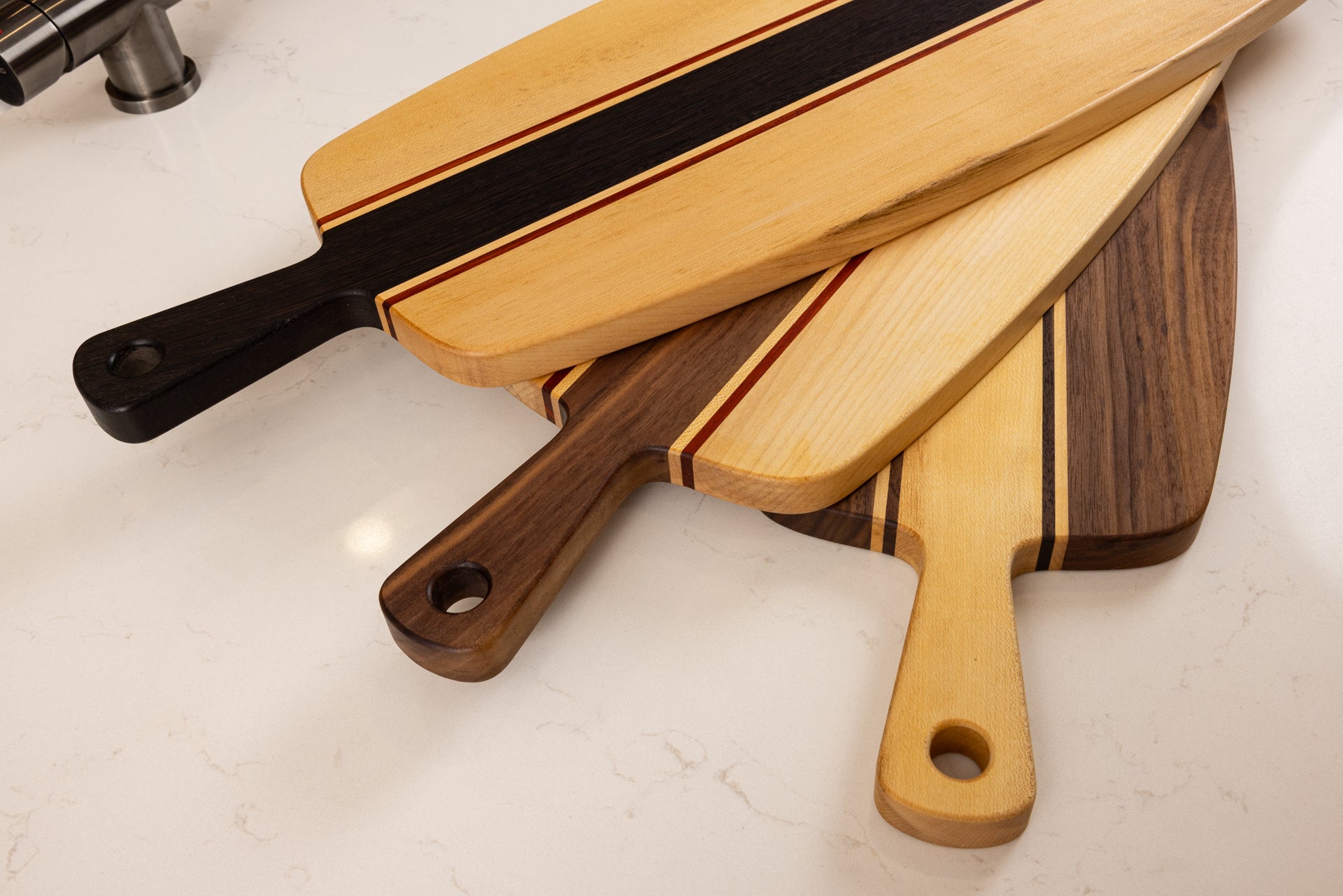 Collection de planches apéro artisanales en bois massif, détail des poignées et des différentes essences de bois.